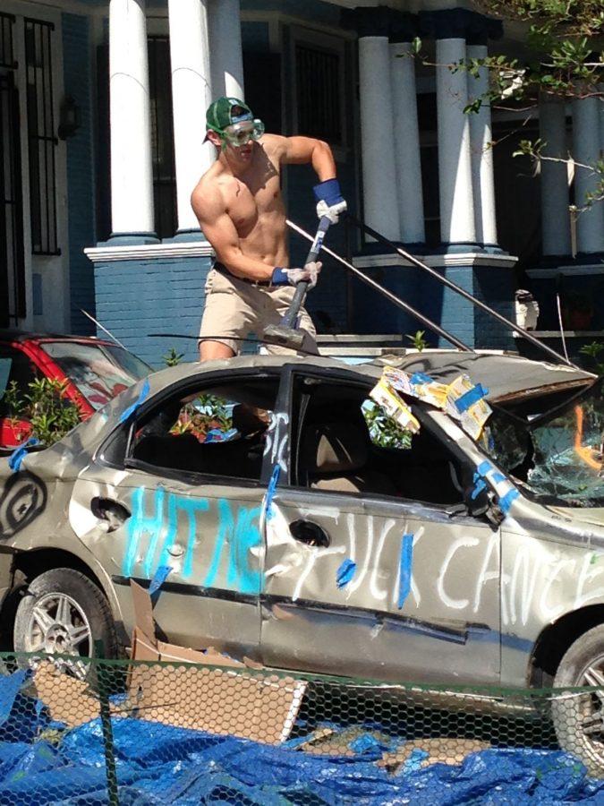 Senior Billy Coombs, cancer survivor and Zeta Psi brother, takes a sledgehammer to a car at the second annual Car Bash. 