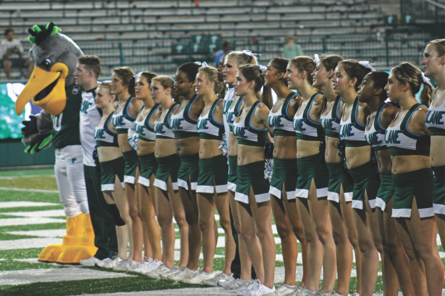 The cheerleading team stands in the end zone facing the student section after a Tulane home football game. The cheerleaders cheer at every football game, home and away, and stay from before the game starts until the end.