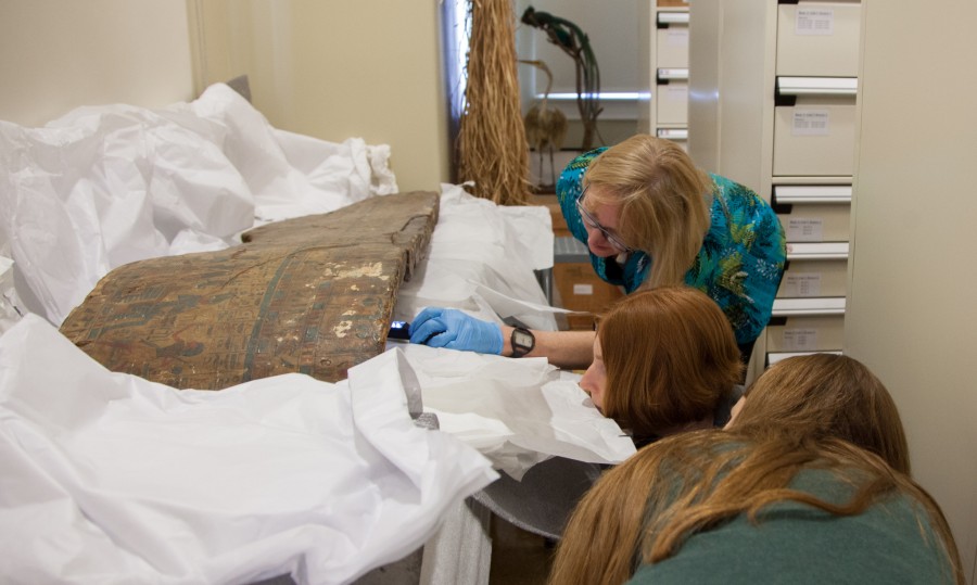 Mimi Leveque (back), Melinda Nelson-Hurst (middle) and Caroline Parris (front) examine part of the coffin of Amenemope.