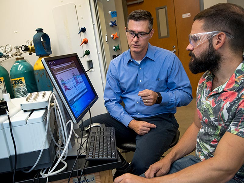 Professor Daniel Shantz (left) and graduate student Ross Ransom analyze data from their research of zeolite SSZ-39 in an effort to reduce harmful chemicals in auto emissions. 
