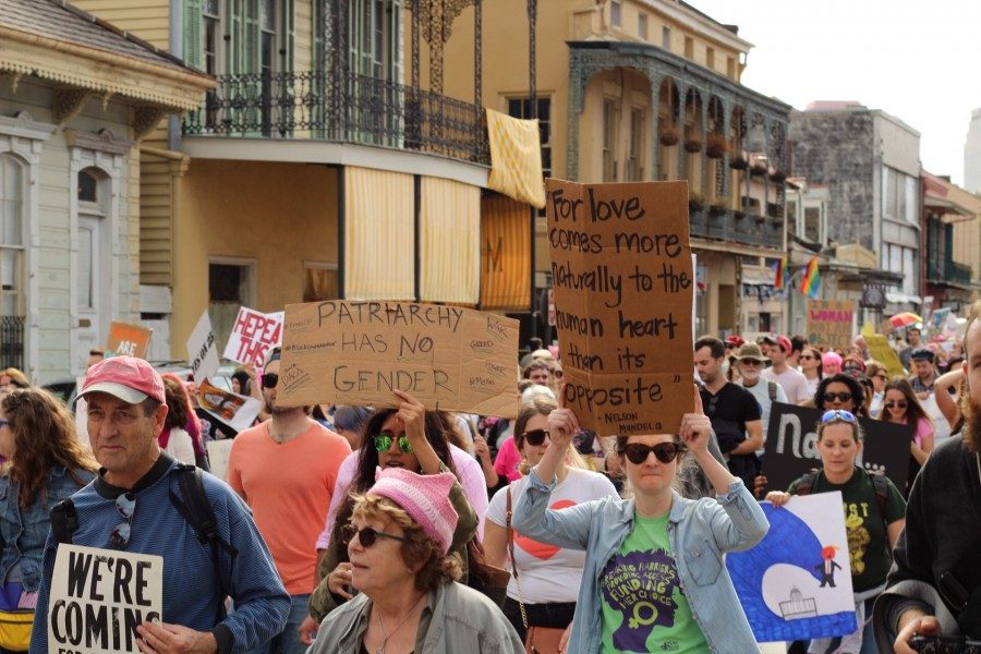 Participants in the 2018 Womens March walk through the streets of Downtown New Orleans holding signs.