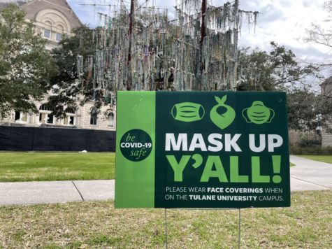 A masking sign on Tulane's campus in front of the "Bead Tree" sculpture.