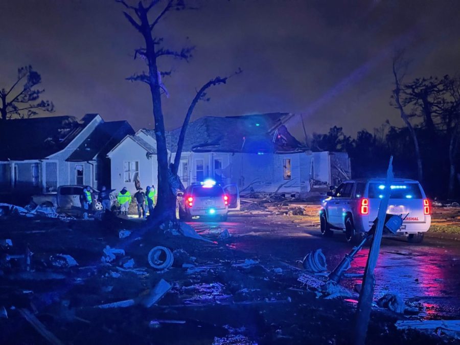 First responders from the Louisiana State Fire Marshal make their way down a debris-laden street, checking each house, door by door.
