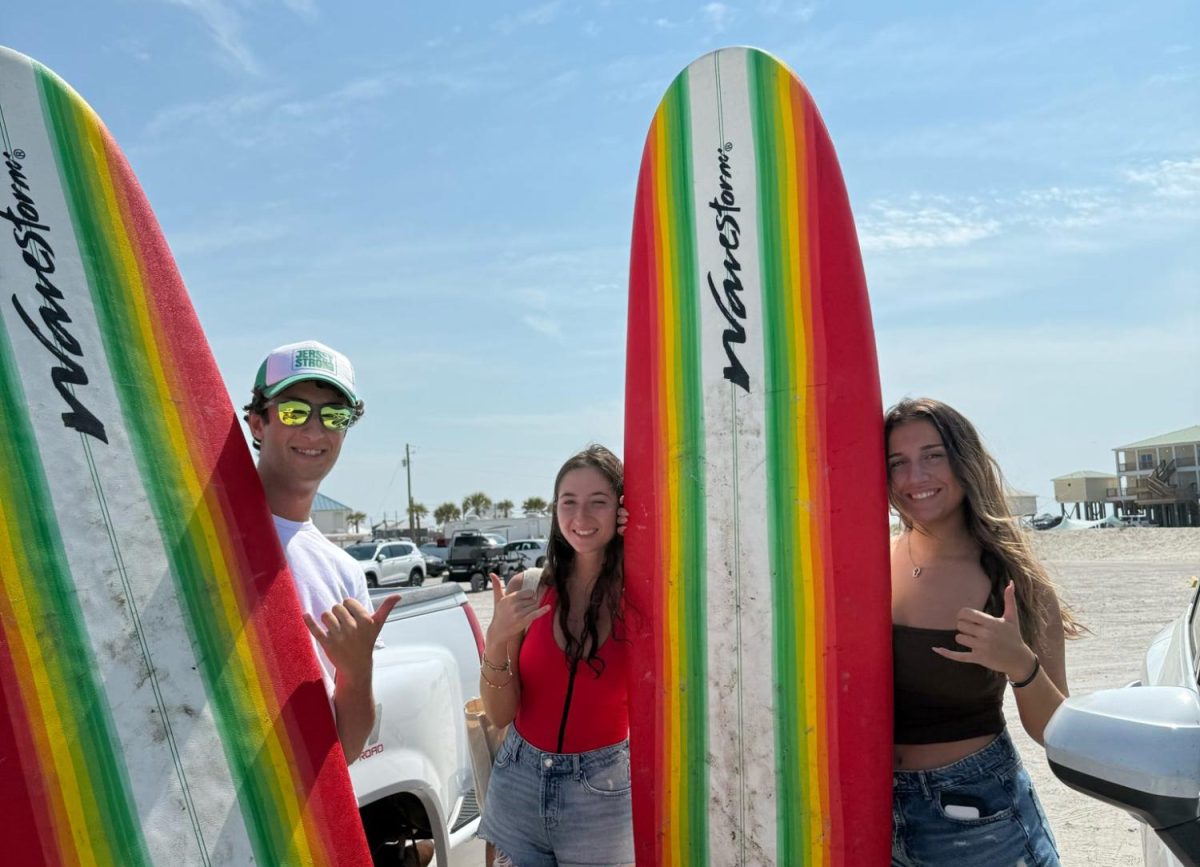 Three members of Tulane Surf Club with their surfboards. 
