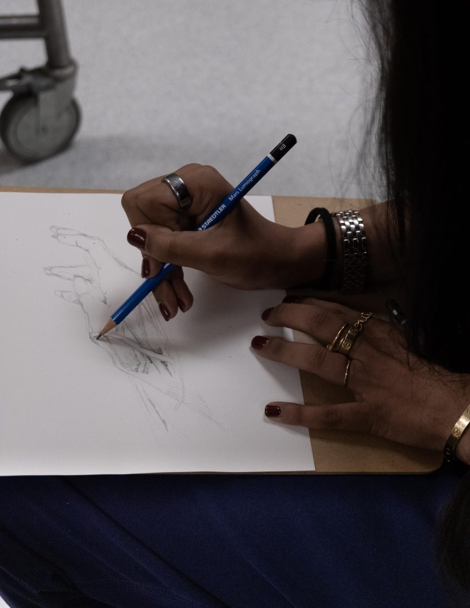 A student creates an anatomical drawing of a hand.